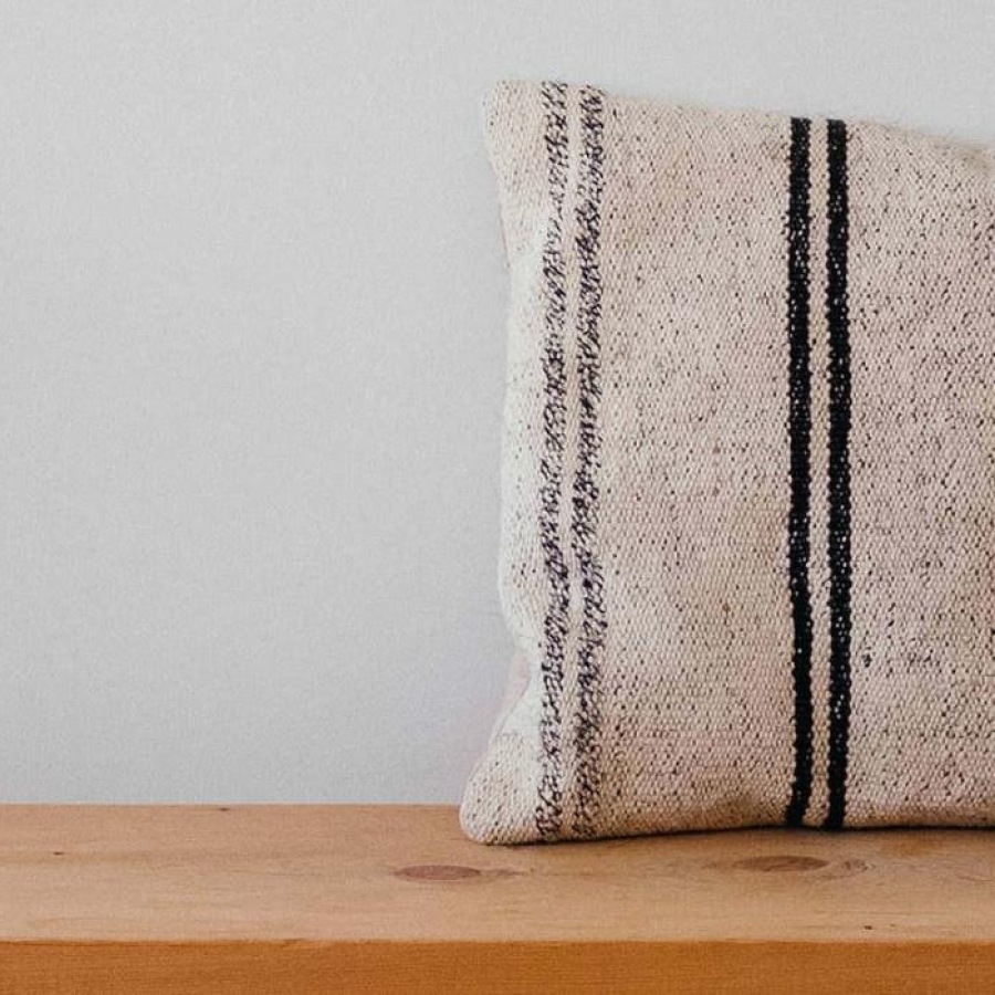 a wooden bench with a striped pillow on it